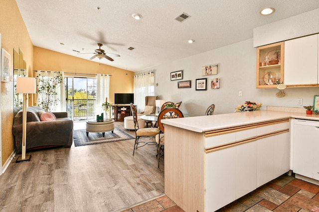 kitchen with kitchen peninsula, light hardwood / wood-style flooring, vaulted ceiling, ceiling fan, and white cabinetry