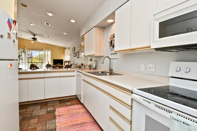 kitchen with vaulted ceiling, white cabinetry, sink, and white appliances