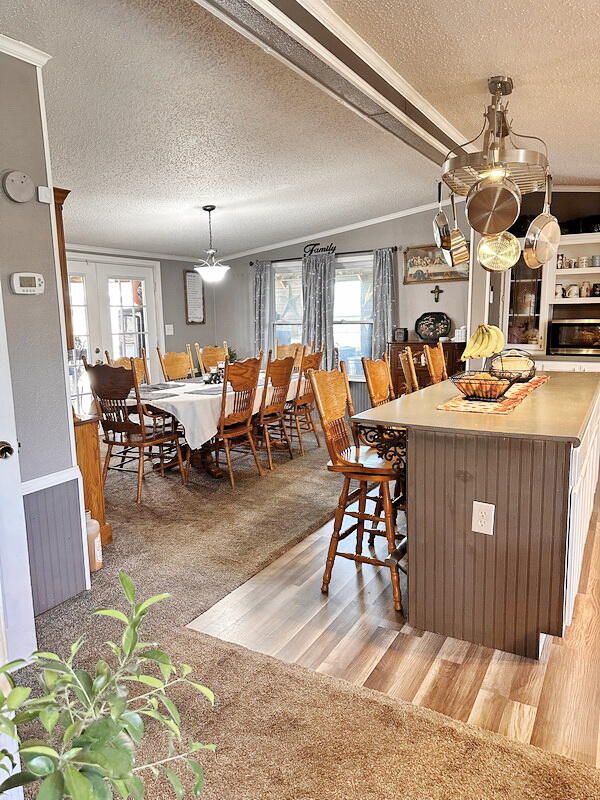 carpeted dining space with french doors, ornamental molding, and a textured ceiling