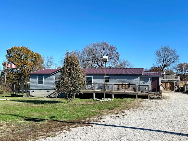 view of front of property featuring a wooden deck, a trampoline, and a front yard