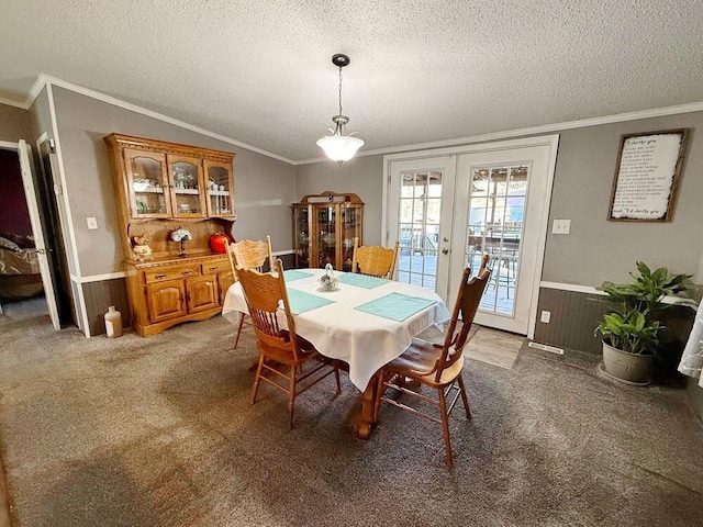 dining area featuring carpet, ornamental molding, a textured ceiling, vaulted ceiling, and french doors