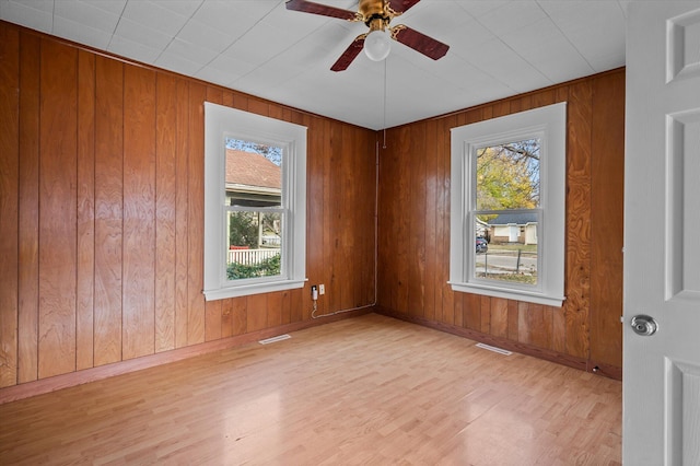 unfurnished room featuring wooden walls, ceiling fan, and light wood-type flooring