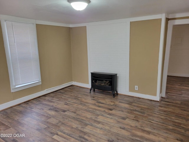 unfurnished living room featuring dark wood-type flooring and a wood stove