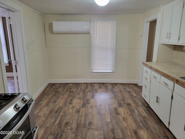 kitchen with dark wood-type flooring, white cabinetry, gas range, a wall mounted AC, and ornamental molding