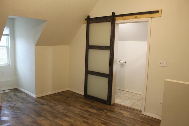 bonus room featuring a barn door, vaulted ceiling, and dark wood-type flooring