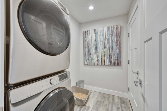 laundry area with stacked washing maching and dryer and light wood-type flooring