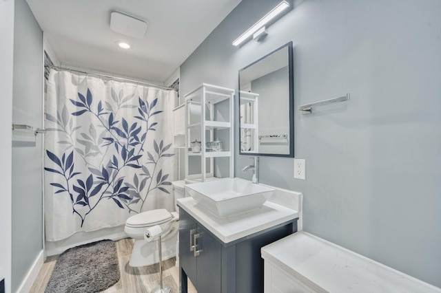 full bathroom featuring hardwood / wood-style flooring, vanity, shower / tub combo with curtain, and toilet