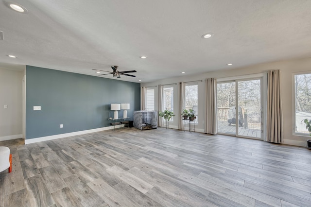 unfurnished living room with a wealth of natural light, a textured ceiling, ceiling fan, and light hardwood / wood-style flooring