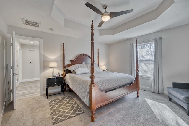 carpeted bedroom featuring ceiling fan and a tray ceiling