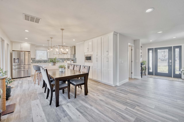 dining space with a wealth of natural light, a notable chandelier, and light hardwood / wood-style floors