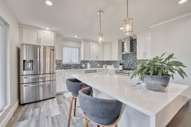 kitchen featuring white cabinetry, sink, stainless steel appliances, and wall chimney exhaust hood