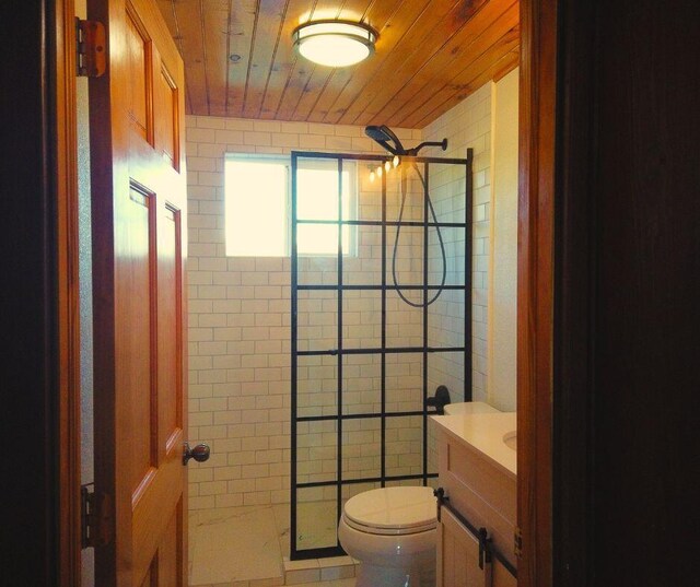 bathroom featuring a tile shower, vanity, toilet, and wood ceiling