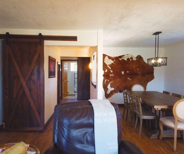 bedroom with a textured ceiling, a barn door, and dark wood-type flooring