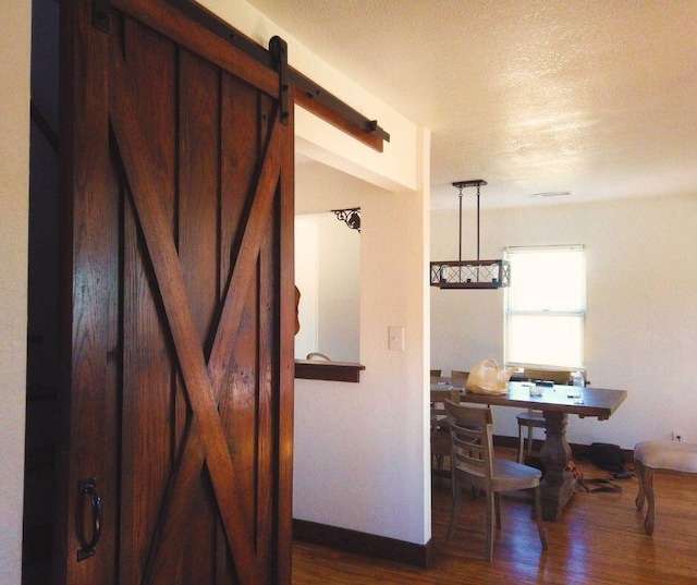 hallway with a barn door, dark wood-type flooring, and a textured ceiling