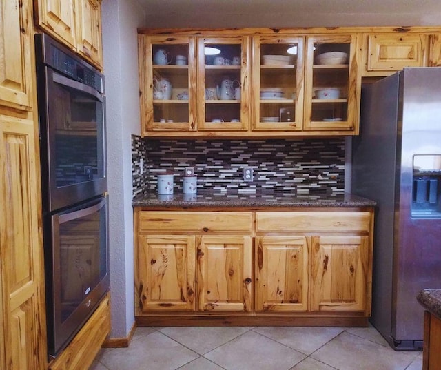 kitchen featuring decorative backsplash, light tile patterned floors, stainless steel refrigerator with ice dispenser, and black double oven