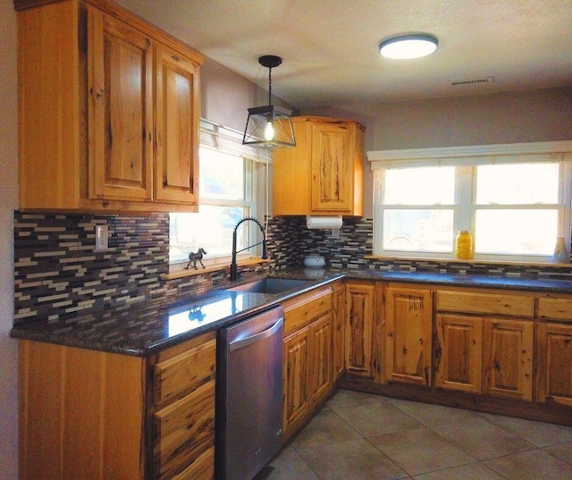 kitchen with sink, tasteful backsplash, stainless steel dishwasher, decorative light fixtures, and dark tile patterned flooring