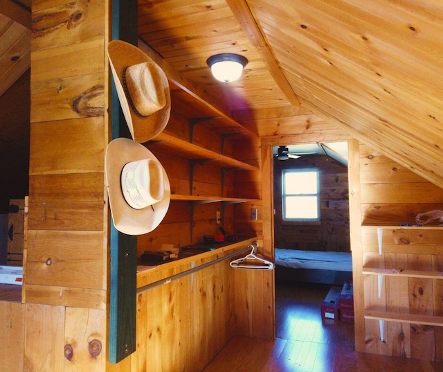 interior space with wood walls, wooden ceiling, vaulted ceiling, ceiling fan, and wood-type flooring