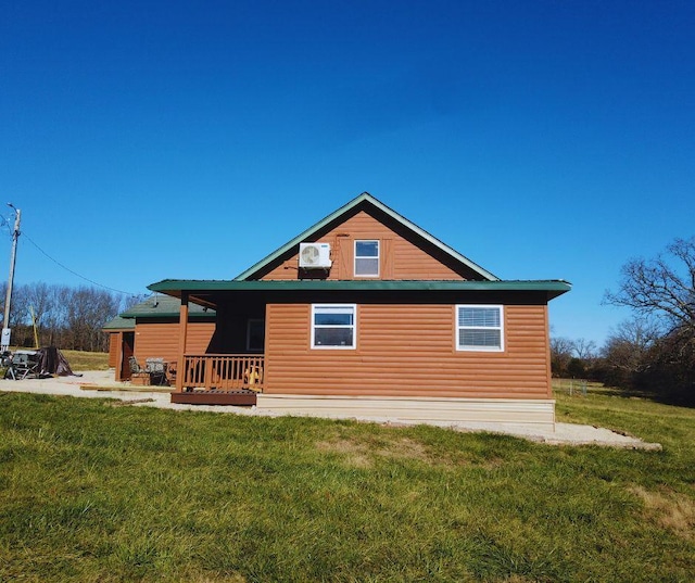 rear view of property with a lawn, a wall unit AC, and a porch