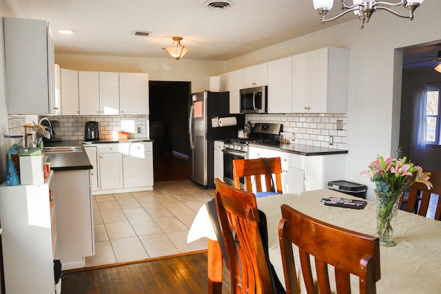 kitchen with stainless steel appliances, white cabinetry, and light hardwood / wood-style flooring