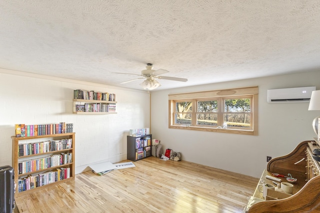 sitting room featuring a wall unit AC, hardwood / wood-style floors, and a textured ceiling