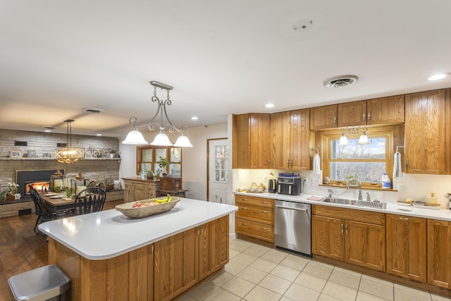 kitchen with a large fireplace, sink, dishwasher, a kitchen island, and hanging light fixtures