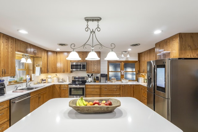 kitchen featuring backsplash, sink, stainless steel appliances, and hanging light fixtures