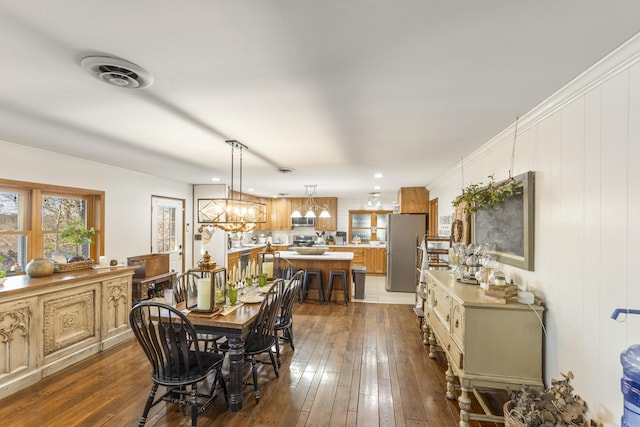 dining space with crown molding, dark hardwood / wood-style floors, and an inviting chandelier