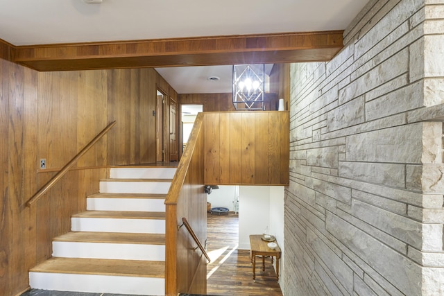 stairway with hardwood / wood-style floors, a notable chandelier, and wooden walls