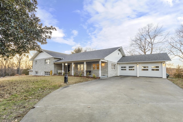 view of front of property with covered porch, a garage, and a front lawn