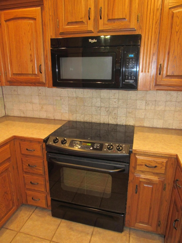 kitchen featuring black appliances, light tile patterned flooring, and backsplash