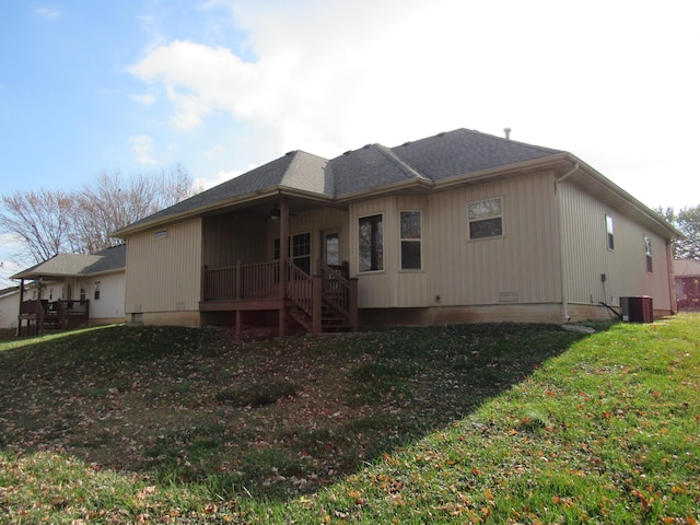 back of house with central AC unit and a lawn