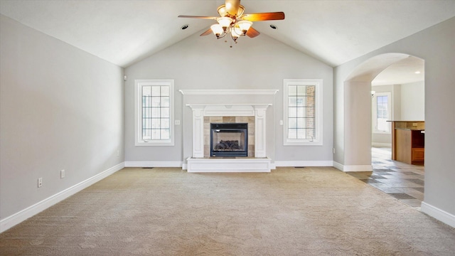 unfurnished living room with a tiled fireplace, light colored carpet, and a healthy amount of sunlight