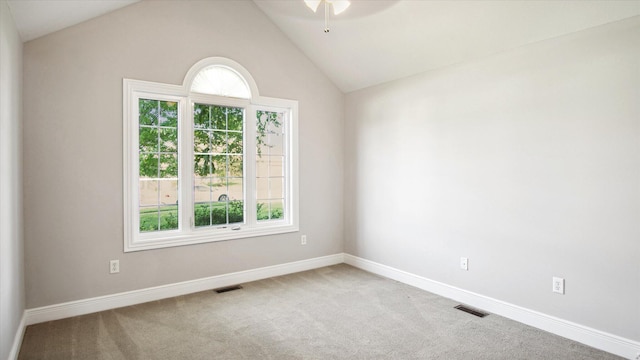 empty room featuring carpet flooring, vaulted ceiling, and a wealth of natural light