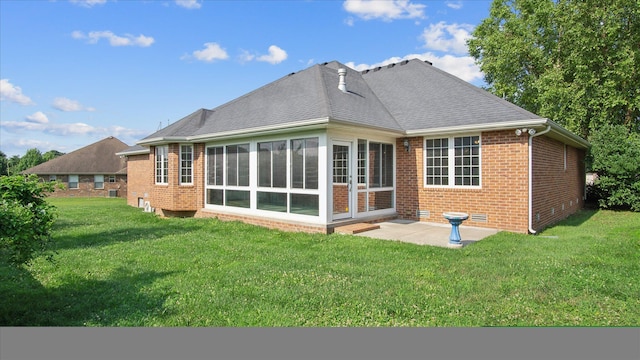 rear view of house featuring a lawn, a sunroom, and a patio area