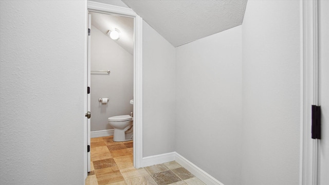 bathroom with toilet, lofted ceiling, and a textured ceiling