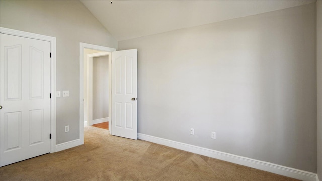 unfurnished bedroom featuring light carpet and lofted ceiling