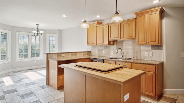 kitchen featuring kitchen peninsula, backsplash, sink, pendant lighting, and a center island