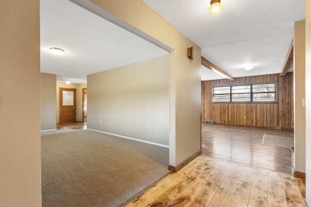 unfurnished room featuring light hardwood / wood-style floors, beam ceiling, and wooden walls