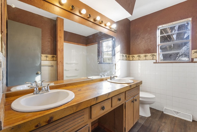 bathroom with wood-type flooring, vanity, toilet, and tile walls