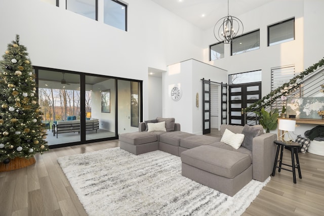 living room featuring light hardwood / wood-style flooring, a towering ceiling, and a chandelier