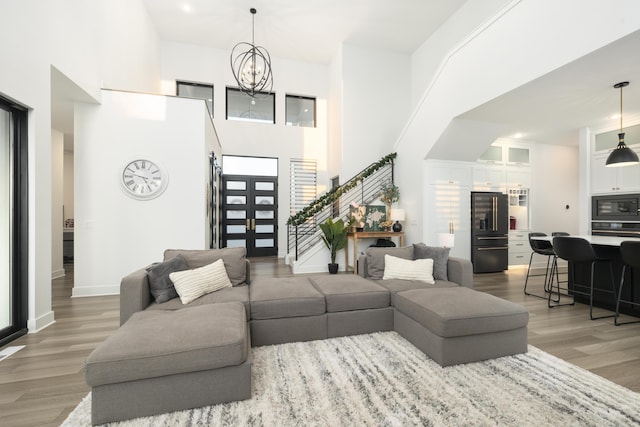 living room featuring hardwood / wood-style flooring, a towering ceiling, and an inviting chandelier