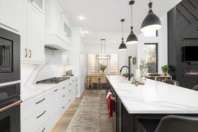 kitchen with white cabinets, black oven, a spacious island, and a breakfast bar area