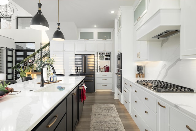 kitchen with white cabinetry, sink, hanging light fixtures, dark wood-type flooring, and built in appliances