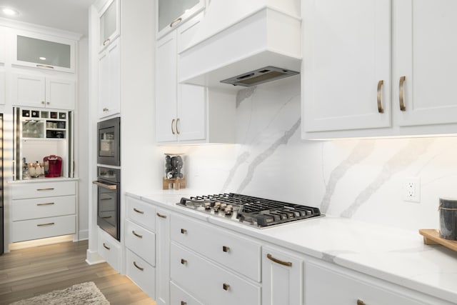 kitchen featuring white cabinetry, stainless steel appliances, and custom exhaust hood