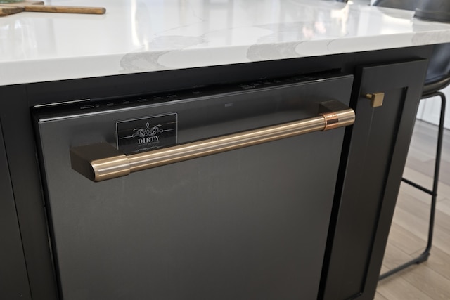 room details featuring stainless steel dishwasher, light hardwood / wood-style floors, and a breakfast bar area