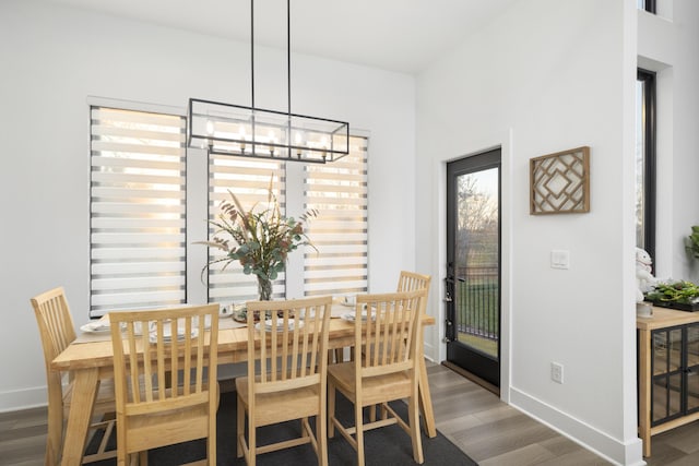 dining area with dark wood-type flooring and an inviting chandelier