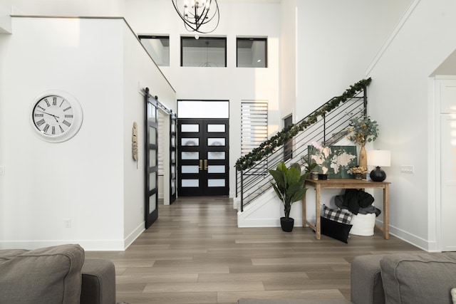 foyer entrance featuring a chandelier, hardwood / wood-style floors, a towering ceiling, and a barn door