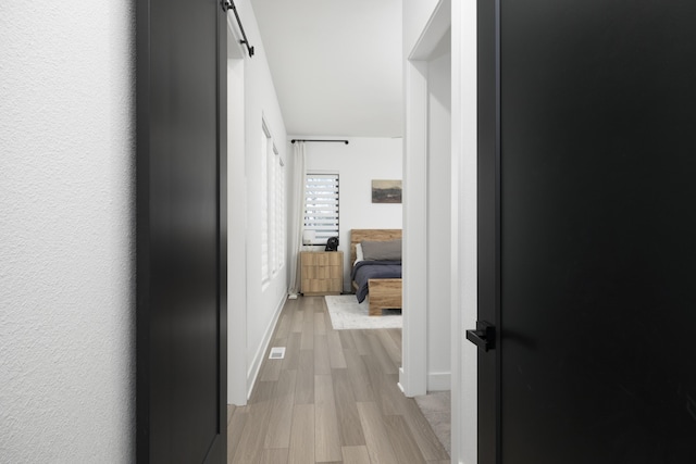 hall with a barn door and light wood-type flooring