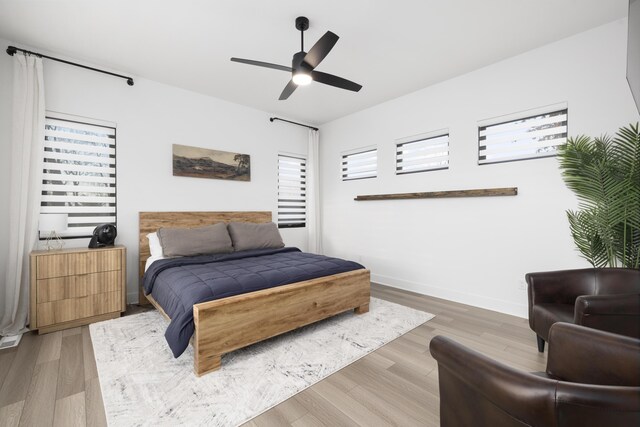 bedroom with ceiling fan, wood-type flooring, and multiple windows