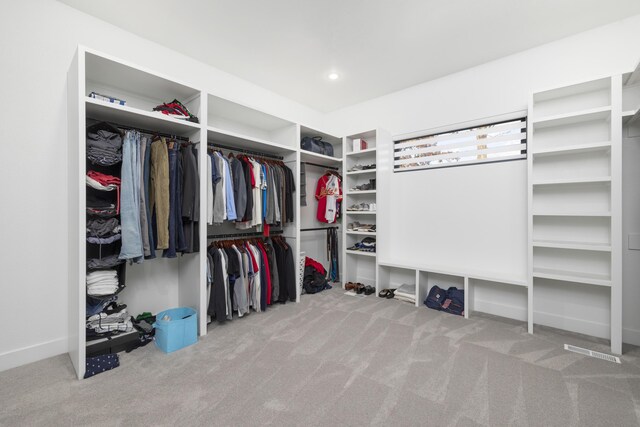 walk in closet with light carpet